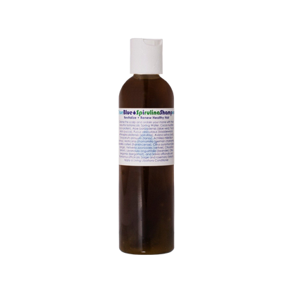 A small brown bottle with a white cap, labeled "True Blue Spirulina Shampoo" from Living Libations. The label also features text about revitalizing and renewing healthy, colored hair with azulene-containing essential oils and a list of botanical ingredients including spirulina, aloe barbadensis, and various extracts.