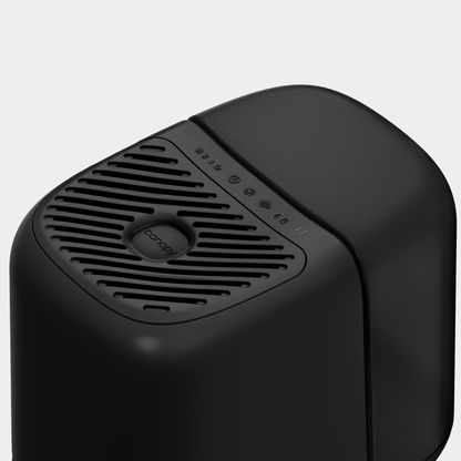 A modern black Bedside Humidifier 2.0 by Canopy, featuring a rounded design and top grille. The front displays icons and text for power and settings, making it an ideal addition to contemporary spaces.