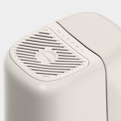 The sleek white Canopy Bedside Humidifier 2.0 features a vented top with the brand logo and control symbols for power and humidity levels on its smooth surface. Its minimalist design is crafted to keep your air purified and enhance comfort.