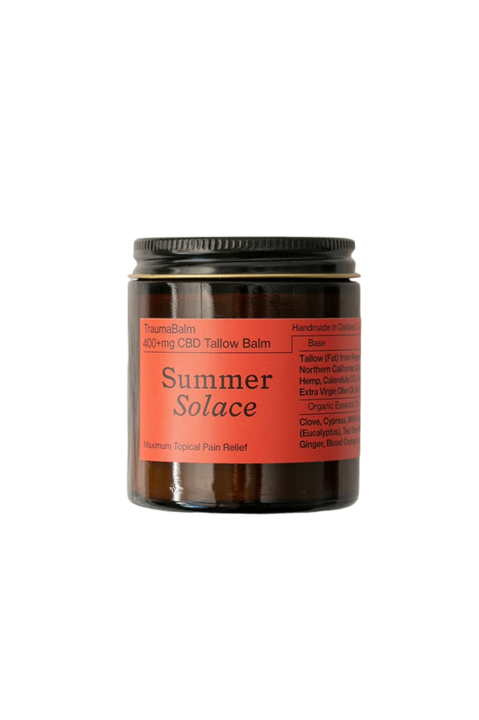 A brown glass jar labeled "TraumaBalm Soothe Soreness - Regenerative Tallow™" with an orange label that reads "Summer Solace Tallow," "Maximum Topical Pain Relief." The jar features a black screw-on lid and a list of ingredients, highlighting Onda herbal infusion's anti-inflammatory benefits, and notes "Handmade in Oakland, CA" on the label.