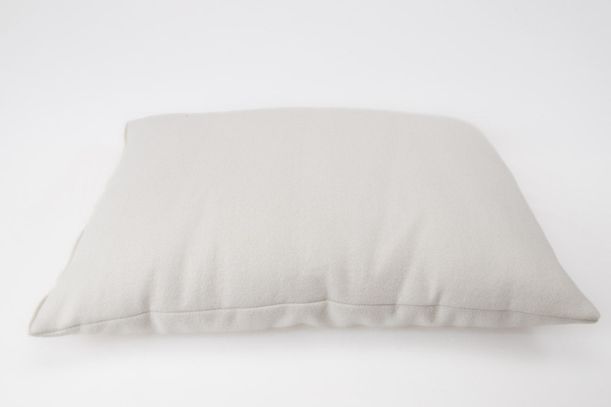 A soft, light gray All Wool Dream Pillow by Shepherd's Dream rests on a plain white background, highlighting its rectangular shape and smooth texture while providing allergen-reducing benefits.