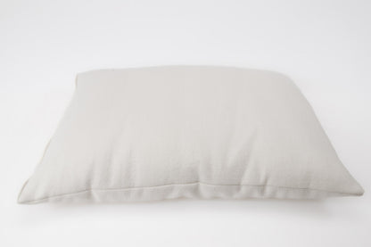 A soft, light gray All Wool Dream Pillow by Shepherd's Dream rests on a plain white background, highlighting its rectangular shape and smooth texture while providing allergen-reducing benefits.