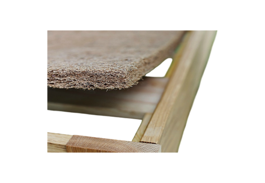 Close-up of a wooden frame with the CocoCoir Comfort Pad by Shepherd's Dream resting on top, showcasing its textured, woven coconut coir design. The focus is on the corner of the frame and the edge of the pad, emphasizing the contrast between the smooth wood and its rough texture.