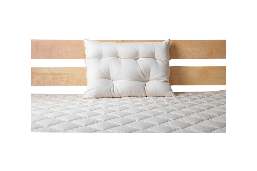 A neatly made bed showcases a light wood headboard with a single white pillow resting against it. The bedspread, quilted in a diamond pattern, rests on the Cascade Latex Mattress by Shepherd's Dream, ensuring restful nights.