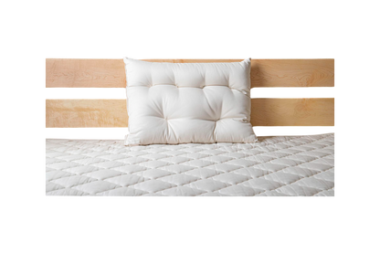 A neatly made bed showcases a light wood headboard with a single white pillow resting against it. The bedspread, quilted in a diamond pattern, rests on the Cascade Latex Mattress by Shepherd's Dream, ensuring restful nights.