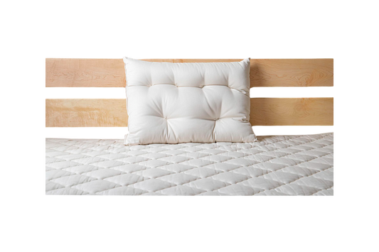 A neatly made bed showcases a light wood headboard with a single white pillow resting against it. The bedspread, quilted in a diamond pattern, rests on the Cascade Latex Mattress by Shepherd's Dream, ensuring restful nights.