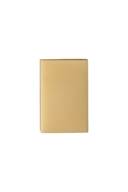 A plain, square-shaped, tan soap bar with smooth edges and minimal texture, set against a solid black background. Infused with Lemon Basil essential oil, the simple design and neutral color give the Violet and Lemon Basil A2/A2 Milk Soap - Regenerative Tallow® by Summer Solace Tallow a clean and minimalist appearance.