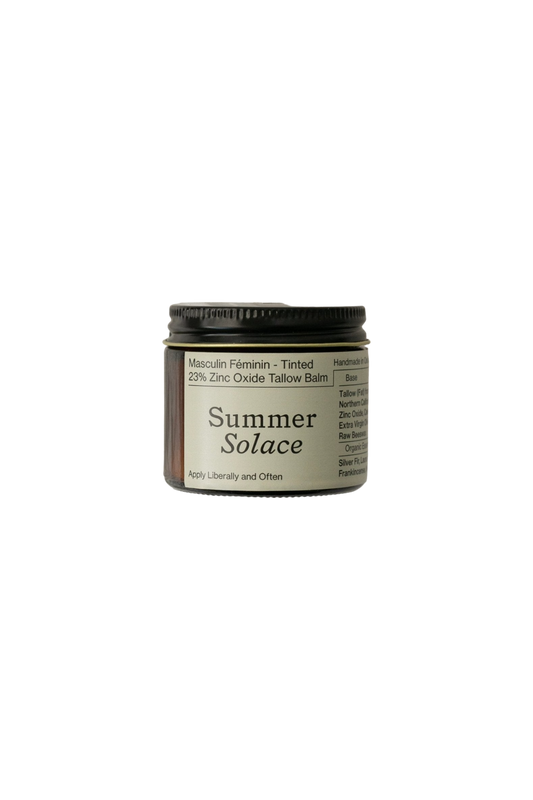 A small, dark-colored jar of "Zinc Oxide Tallow Balms-Regenerative Tallow®" from Summer Solace Tallow, labeled "Masculin Féminin - Tinted," contains 23% Zinc Oxide. The glass container with a screw-on lid features instructions to "Apply Liberally and Often." Its natural formulation can even serve as an effective insect repellent.